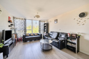 Spacious living room with large windows, black sofas, coffee table and TV setup