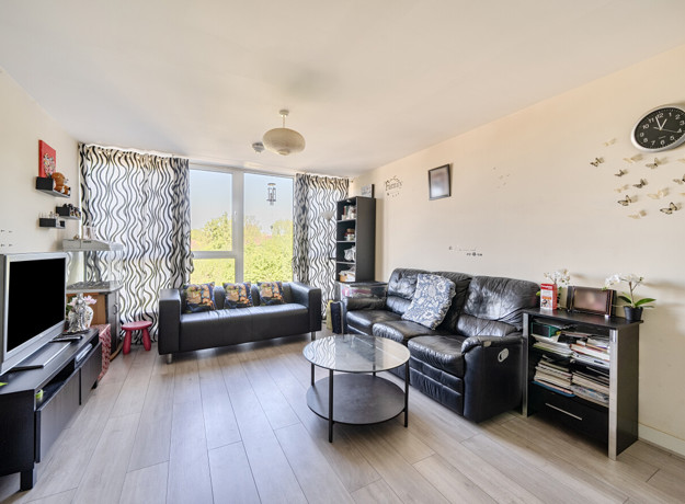 Spacious living room with large windows, black sofas, coffee table and TV setup
