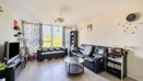 Spacious living room with large windows, black sofas, coffee table and TV setup