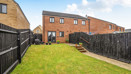 Rear garden with lawn, fencing and row of houses at the back.