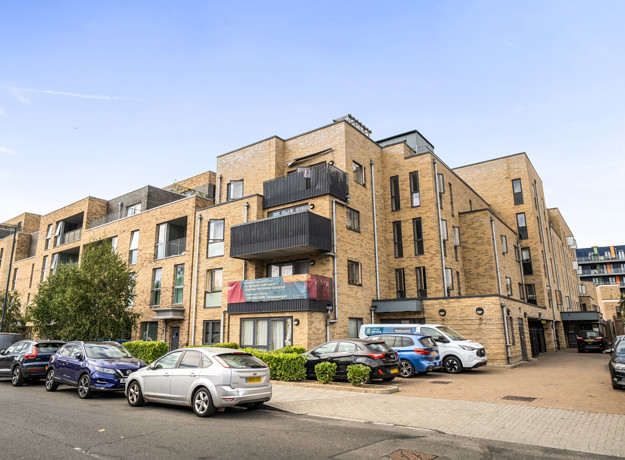 Exterior view of apartment building with balconies and resident parking.