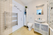 Bathroom with tiled walls, bathtub, toilet, sink unit and wall-mounted towel rail