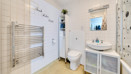 Bathroom with tiled walls, bathtub, toilet, sink unit and wall-mounted towel rail