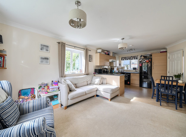 Open plan living area with sofas leading to dining space and kitchen.