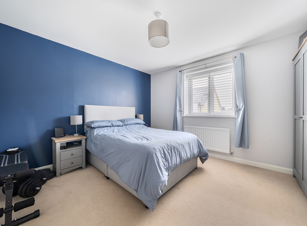 Minimal bedroom with blue accent wall, single bed, and wardrobe by window.