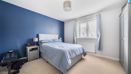 Minimal bedroom with blue accent wall, single bed, and wardrobe by window.