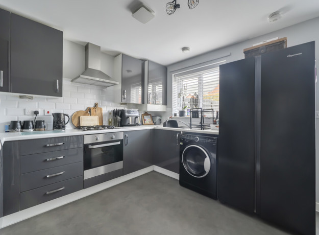 Modern kitchen with grey cabinets, appliances, and black fridge freezer.