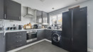 Modern kitchen with grey cabinets, appliances, and black fridge freezer.