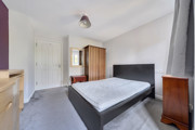 Bedroom with double bed, wardrobe, chest of drawers and mirror.