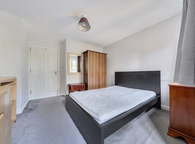 Bedroom with double bed, wardrobe, chest of drawers and mirror.