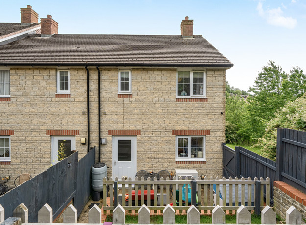 Rear view of brick house with terraced garden with fencing and patio doors.