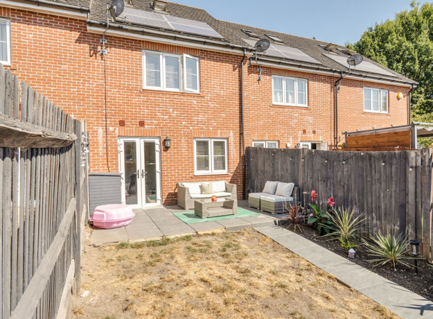 Rear garden with patio area, fencing and red brick house exterior.