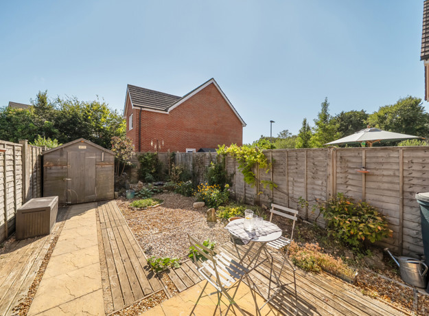 Rear garden with patio seating area, plants, shed and fenced boundaries.
