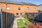 Rear garden with lawn, fencing and terraced houses in the background