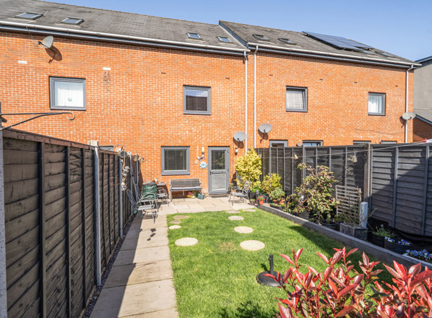 Rear garden with lawn, fencing and terraced houses in the background
