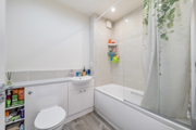 Bathroom with bathtub, shower screen, toilet and washbasin.