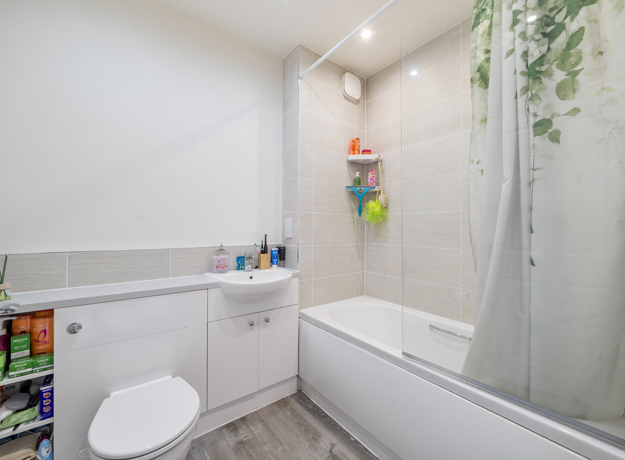 Bathroom with bathtub, shower screen, toilet and washbasin.