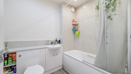 Bathroom with bathtub, shower screen, toilet and washbasin.