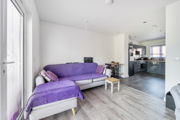 Open-plan living space with sofa, coffee table, dining table with chairs and kitchen area.