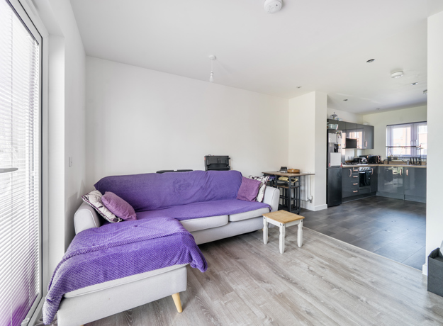 Open-plan living space with sofa, coffee table, dining table with chairs and kitchen area.
