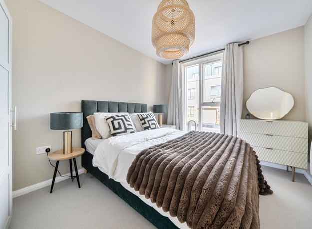 Bedroom with double bed, bedside tables and large window.