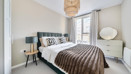 Bedroom with double bed, bedside tables and large window.