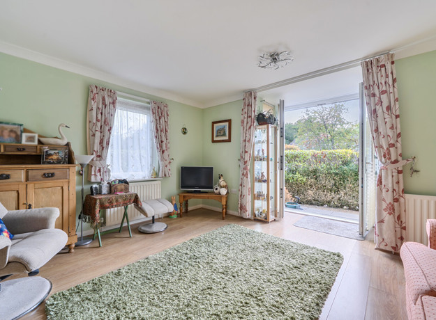 Living room with seating, shelving, windows and patio doors.