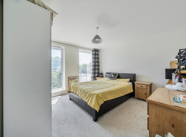 Bedroom with double bed, fitted furniture and a window.