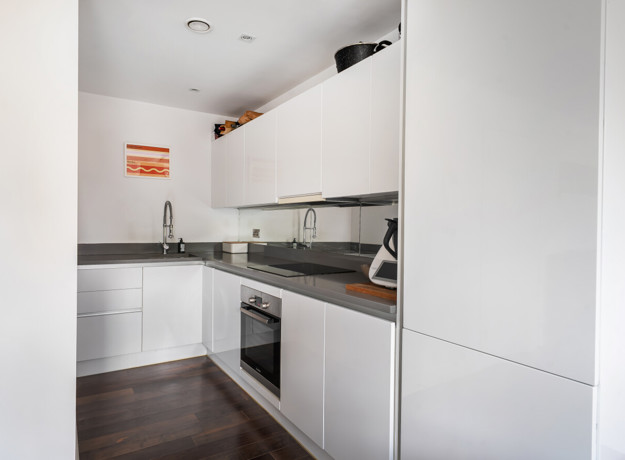 Compact white kitchen with fitted cabinets, worktops and built-in appliances.
