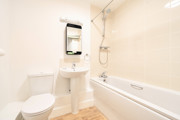 Bathroom with toilet, sink, mirror and bathtub with tiled walls.