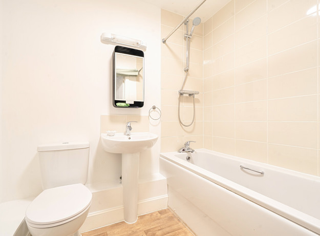 Bathroom with toilet, sink, mirror and bathtub with tiled walls.