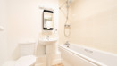 Bathroom with toilet, sink, mirror and bathtub with tiled walls.