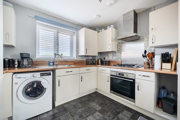 Kitchen with white cabinets, washing machine, and wood effect countertop.
