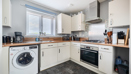 Kitchen with white cabinets, washing machine, and wood effect countertop.