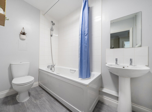 Bathroom with a toilet, sink, bathtub and shower curtain.