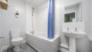 Bathroom with a toilet, sink, bathtub and shower curtain.