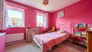 Bright pink bedroom with single bed, shelving, desk and window providing natural light