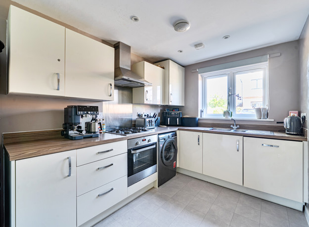 Contemporary kitchen with white cabinets, integrated oven and large window