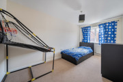 Bedroom with metal bunk bed, blue bedding and window with curtains