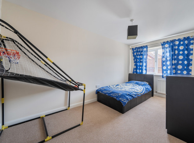 Bedroom with metal bunk bed, blue bedding and window with curtains