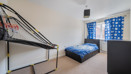 Bedroom with metal bunk bed, blue bedding and window with curtains