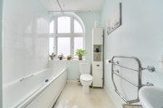 Bathroom with bathtub, toilet, sink, towel rail, and tiled walls with window.
