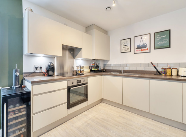 Kitchen with white cabinets, integrated oven and countertop appliances.