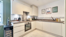 Kitchen with white cabinets, integrated oven and countertop appliances.