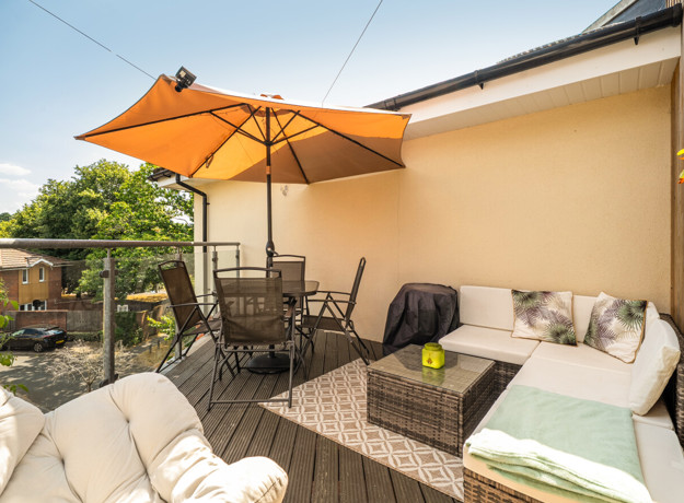 Patio with outdoor seating, a dining table and a large parasol.