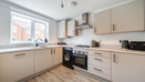 Modern kitchen with white cabinets, light coloured worktops, integrated appliances and window.