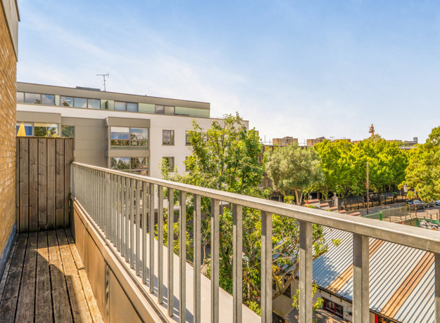 Balcony with metal railing overlooking nearby buildings and trees.