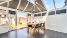 Conservatory with glass roof, tiled floor, and wooden dining table with chairs.