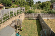 Elevated view of a fenced rear garden with grass and patio areas.
