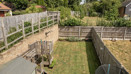 Elevated view of a fenced rear garden with grass and patio areas.